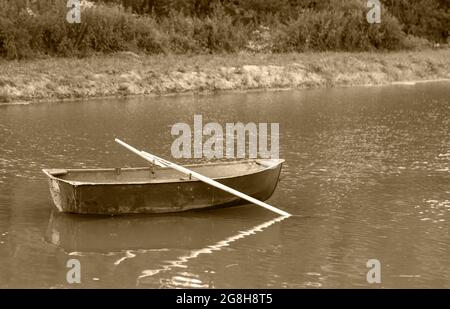 Bateau de pêche vide avec des oars au milieu du lac, photo en noir et blanc Banque D'Images