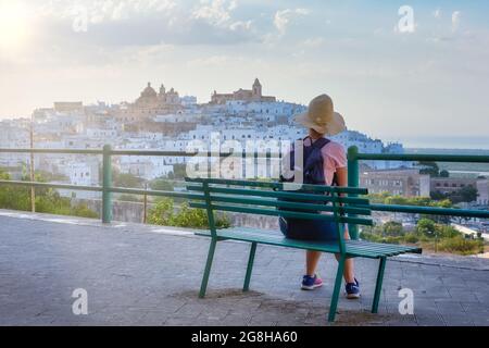 Jeune touriste appréciant la vue sur Ostuni au coucher du soleil assis sur un banc, Puglia Banque D'Images