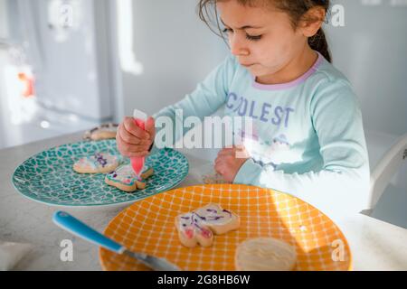 Petite fille décorant des biscuits de pâques avec du glaçage Banque D'Images