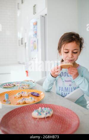 Petite fille décorant et mangeant des biscuits de pâques Banque D'Images