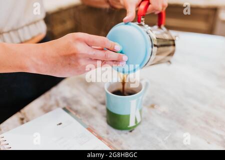 Gros plan de la femme qui verse du café dans une tasse à l'aide de la presse française Banque D'Images
