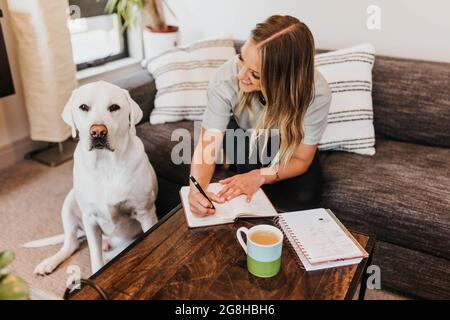 Une femme écrit dans un ordinateur portable tout en regardant son chien Banque D'Images