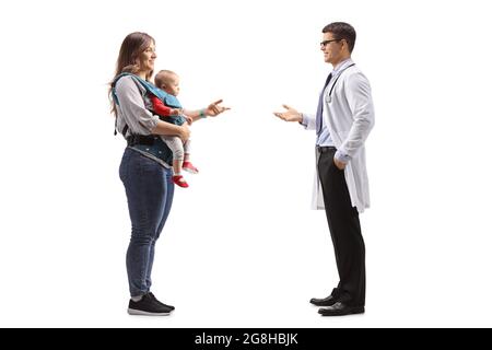 Prise de vue en profil d'un médecin et d'une mère avec un bébé dans un porteur ayant une conversation isolée sur fond blanc Banque D'Images