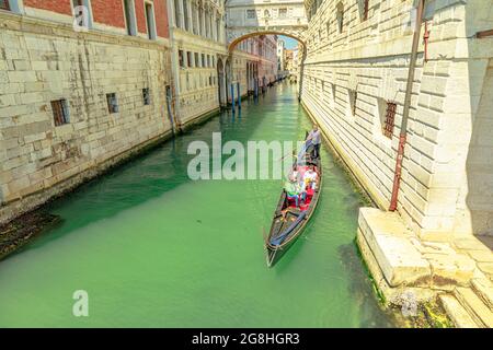 Venise, Italie - 9 mai 2021 : croisière touristique en gondole romantique sous le pont d'arcade Sospiri menant aux anciennes prisons du Palais de Doge. Canaux étroits de Banque D'Images