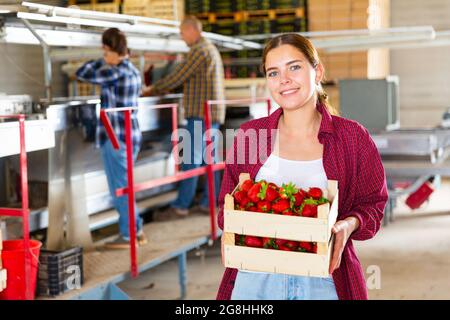 Femme tenant une boîte de fraises à l'entrepôt de fruits Banque D'Images