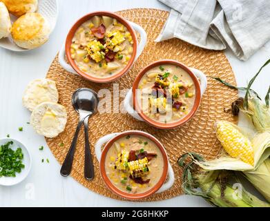 Vue de dessus de trois bols de soupe de poulet et de chaudrée de maïs servis avec des biscuits. Banque D'Images