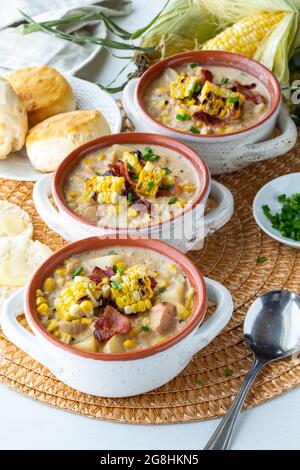 Trois croquettes de soupe dans une rangée remplie de poulet et de chaudrée de maïs et garnies de maïs grillé, de bacon et de ciboulette. Banque D'Images
