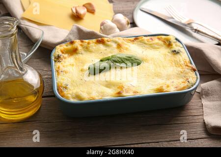 Plat de cuisson avec de savoureuses lasagnes vertes et des ingrédients sur fond de bois Banque D'Images