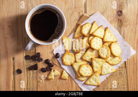 Une tasse de café chaud et des craquelins au fromage sur une ancienne table en bois, vue du dessus Banque D'Images