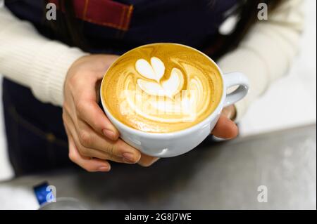 Mains d'un jeune barista qui prépare du café latte Banque D'Images