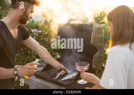 Homme cuisant du poisson sur un grill Banque D'Images