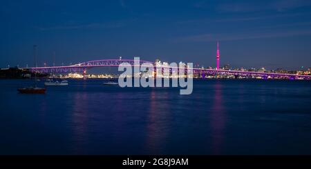 Le Sky Tower d'Auckland est illuminé en rose et le Harbour Bridge en violet Banque D'Images