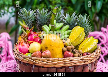 Une grande variété de fruits exotiques dans un panier sur fond vert Banque D'Images