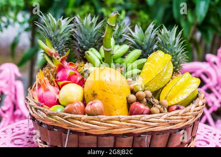 Une grande variété de fruits exotiques dans un panier sur fond vert Banque D'Images