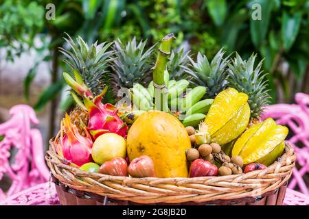 Une grande variété de fruits exotiques dans un panier sur fond vert Banque D'Images