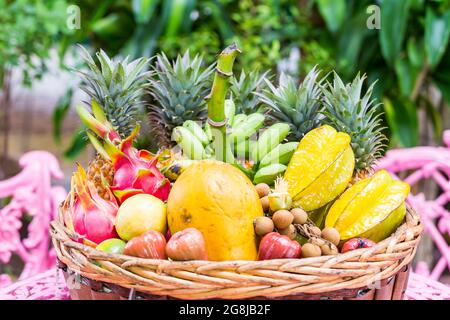 Une grande variété de fruits exotiques dans un panier sur fond vert Banque D'Images