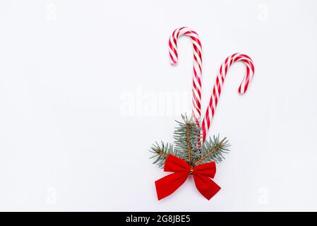 le concept de cristmas avec canne à sucre strippy et arbre de pin avec noeud rouge isolé sur fond blanc, carte de voeux, espace de copie Banque D'Images