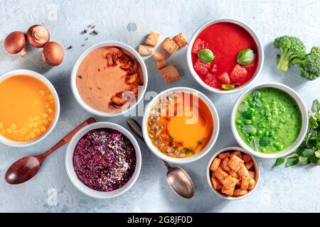 Soupes de légumes colorées, régime végétalien. Citrouille, champignons, betteraves, tomates, maïs doux et crèmes de puseille de pois verts, tiré du dessus avec des ingrédients Banque D'Images