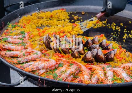 Paella cuite aux crevettes, musse, riz dans une immense casserole au festival de la nourriture de rue Banque D'Images