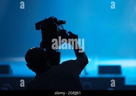Silhouette d'un caméraman avec une caméra vidéo engagée dans le tournage vidéo dans le hall. Banque D'Images