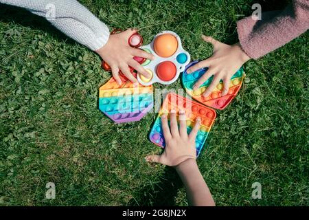 Les enfants tirent les mains pour faire glisser les jouets sur l'herbe verte Banque D'Images