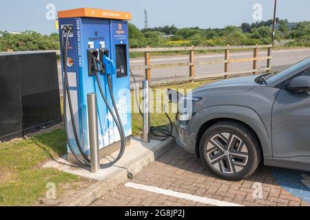 Une voiture électrique branchée à une station de charge Banque D'Images