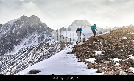 Homme et femme randonneurs avec sac à dos marchant sur le rocher dans les belles montagnes au coucher du soleil Banque D'Images