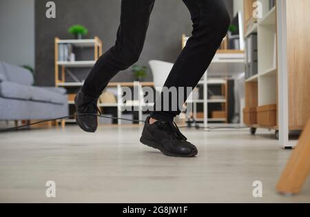 Gros plan sur les pieds d'un homme qui voyage au-dessus d'un cordon électrique à la maison ou au bureau Banque D'Images