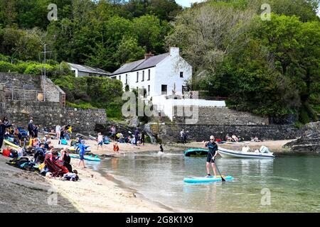 Les gens apprécient leur temps sur la plage dans la pittoresque MCG-yr-Eglwys, Pembrokeshire, au sud du pays de Galles. Il a été rapporté que le petit village de bord de mer a plus de maisons de vacances que les résidents permanents, avec les locaux étant hors prix du marché de l'immobilier. Seulement deux des cinquante propriétés du village abritent maintenant des locaux. Banque D'Images