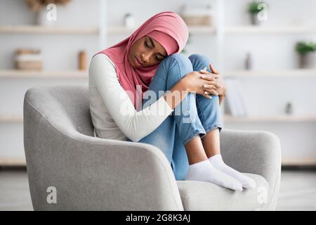 Concept de mélancolie. Une femme musulmane noire déprimée dans le hijab se sentant bouleversée à la maison Banque D'Images
