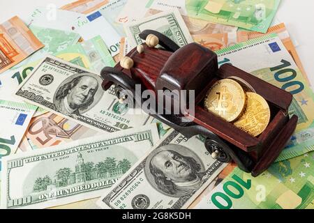 machine en bois avec bitcoins sur fond de texture euro et dollars Banque D'Images