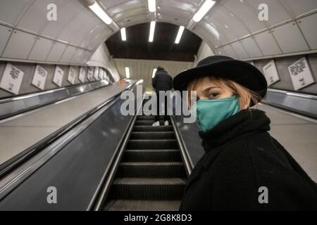 Portrait d'une fille blonde portant un masque sur l'escalier roulant de la station de métro de Londres, Londres, 3 février 2021 Banque D'Images