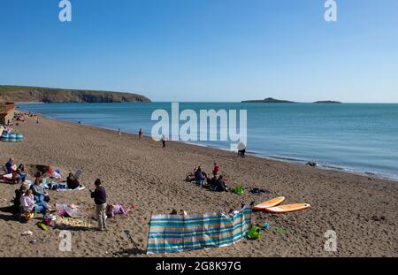 Aberdaron - pays de Galles - avril 3 2021 : scène traditionnelle de bord de mer les vacanciers se détendent sur une plage de sable fin sous un ciel bleu clair aspect paysage avec c Banque D'Images