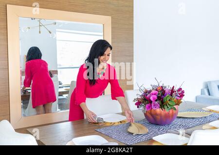 Beauté brune femme avec de longs cheveux et robe rouge est la décoration de la table avec un arrangement de fleur à l'intérieur d'une citrouille peinte de couleur pour célébrer un d Banque D'Images