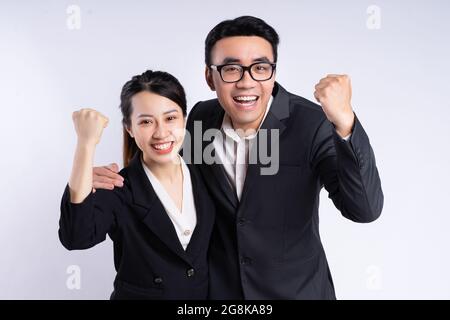 Jeunes employés vietnamiens en costume avec des poings surélevés sur fond de mur Banque D'Images