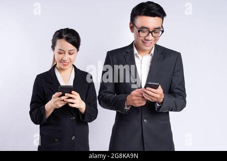 Les jeunes employés vietnamiens en costume souriant tout en utilisant leur téléphone Banque D'Images