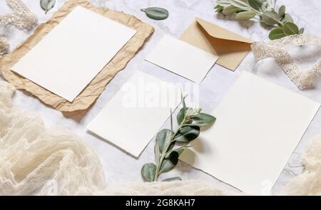 Ensemble de papeterie de mariage avec enveloppe sur une table en marbre décorée de branches d'eucalyptus et de rubans. Scène de maquette avec message d'accueil papier vierge Banque D'Images