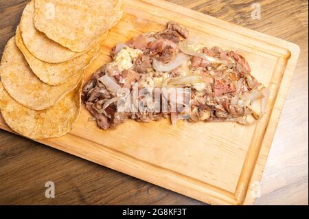 Prise de vue en grand angle de viande hachée cuite avec des oignons sur une planche de bois Banque D'Images