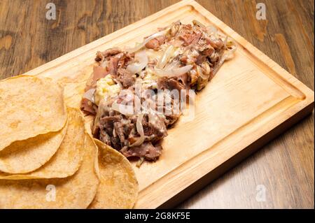 Prise de vue en grand angle de viande hachée cuite avec des oignons sur une planche de bois Banque D'Images