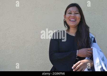 Prise de vue à la taille d'une jeune fille sud-asiatique souriant avec port de kurta noir (robe traditionnelle indienne), debout contre le mur jaune avec regarder l'appareil photo, espace de copie Banque D'Images