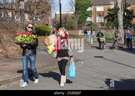 Londres, Royaume-Uni - novembre 2019, les gens marchent entre les stands de vêtements dans un marché aux puces de rue du dimanche à Brick Lane. Un homme et une femme portent acheté Banque D'Images