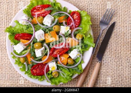 Salade chaude avec potiron, fromage feta, tomates séchées, olives, arugula et oignon rouge. Gros plan. Banque D'Images