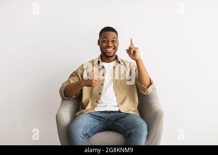 Black Guy gesting Thumbs-Up pointant le doigt vers le haut sur fond gris Banque D'Images