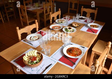 Table au restaurant avec différents plats. Tables et chaises en bois, atmosphère intime sans personnes. Banque D'Images