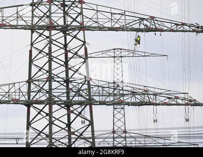 21 juillet 2021, Brandebourg, Ahrensfelde/OT Lindenberg: Un ouvrier pend du boom d'un pylône haute tension par son fusible. Des lignes aériennes à très haute tension sont actuellement mises en place sur une route de 380 kilovolts à l'extérieur de la périphérie nord de Berlin. Photo: Soeren Stache/dpa-Zentralbild/ZB Banque D'Images