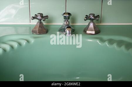 Gros plan sur le lavabo original vert vintage rétro des années 1930 deco et les robinets en acier inoxydable. Banque D'Images