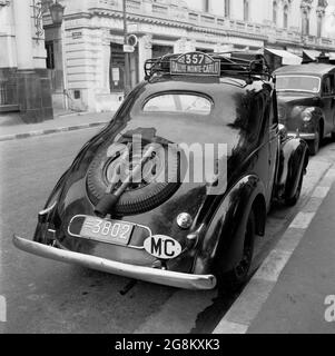 Années 1950, historique, Monaco. Garée dans une rue latérale de Monte-Carlo, une voiture moncao enregistrée, prenant part au rallye de Monte Carlo. Le numéro 357 se trouve sur la galerie de toit. Notez le pickax et la pelle fixés à la roue de secours à l'arrière en pente de la voiture. Banque D'Images