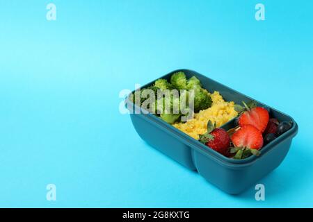 Boîte à lunch avec plats savoureux sur fond bleu Banque D'Images
