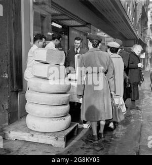 Image historique montrant des femelles à Rouen à l'extérieur, dans la rue, debout par quelques grandes tranches rondes de fromage empilées sur une plate-forme en bois à l'extérieur d'une fromagerie ou d'une crème, France des années 1950 Banque D'Images