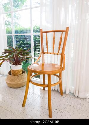 La chaise en bois d'époque se trouve près d'une fenêtre décorée par le rideau blanc dans le petit café, vue de face pour l'espace de copie. Banque D'Images